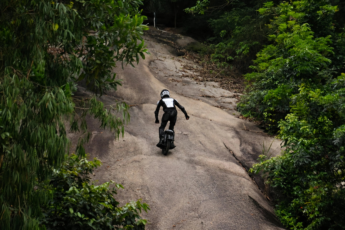 F16 rider navigating a steep rock face surrounded by forest