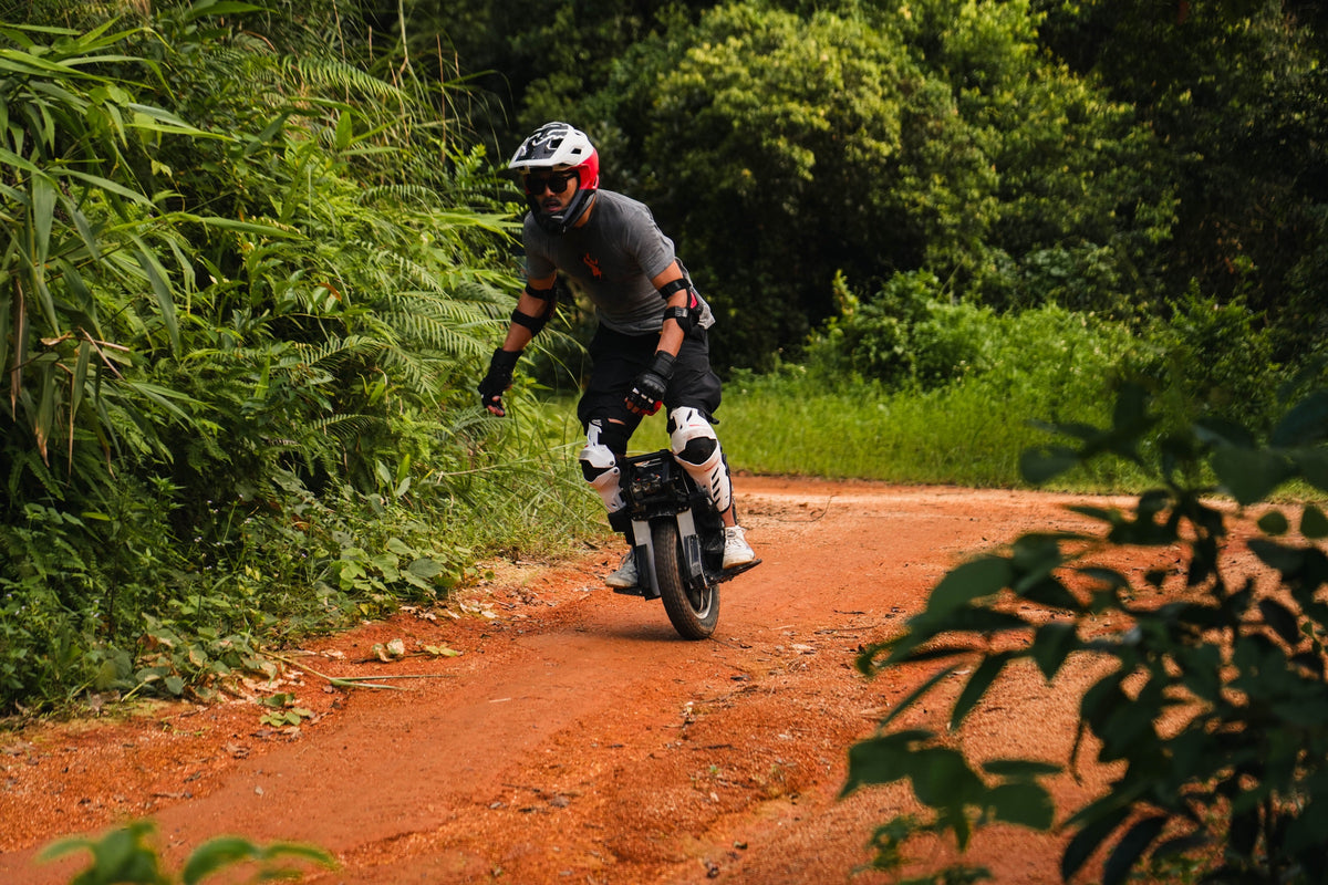 A fully equipped F16 rider following a red-earth trail through lush green woodland